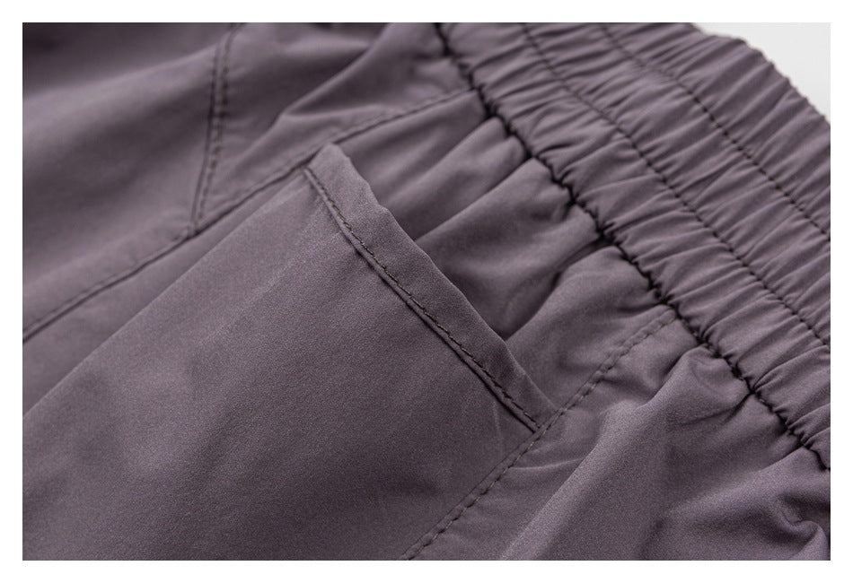 Close-up of mauve-gray shorts showing a slanted pocket opening beside the gathered elastic waistband.