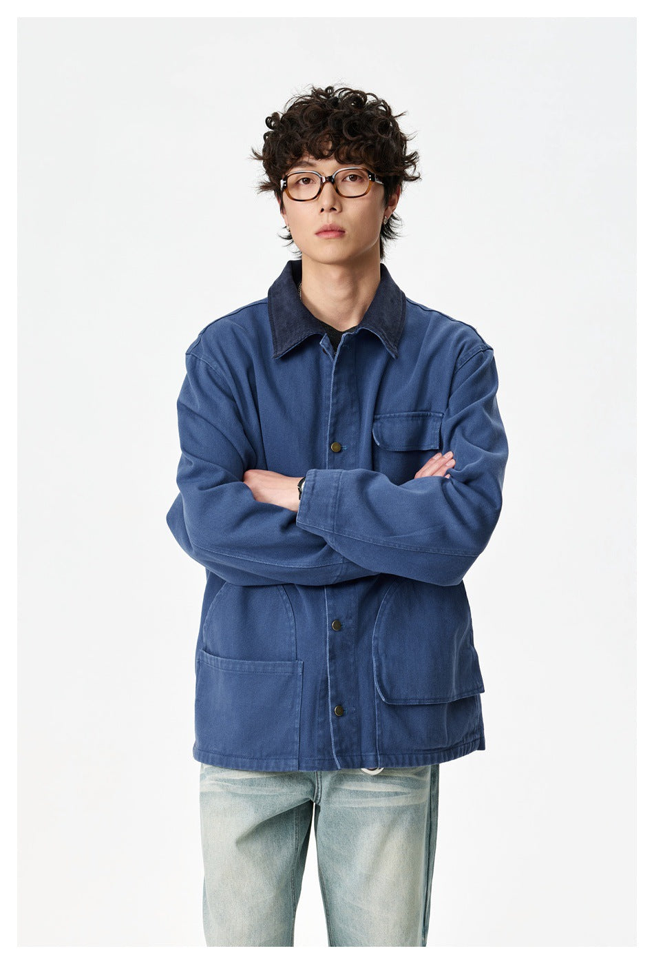 Model with arms crossed wearing a blue chore jacket with navy collar over a dark tee and light washed jeans