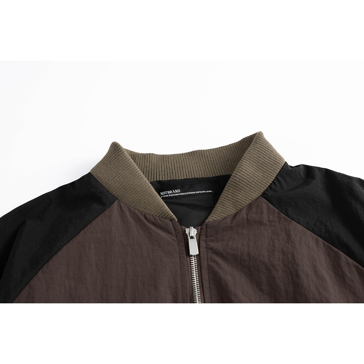 Close-up of a dark brown and black jacket collar with olive ribbing, a silver zipper and an inner label.
