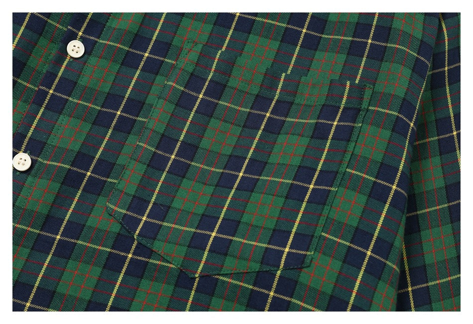 Close-up of the matching chest pocket and buttons on a green and navy tartan shirt.