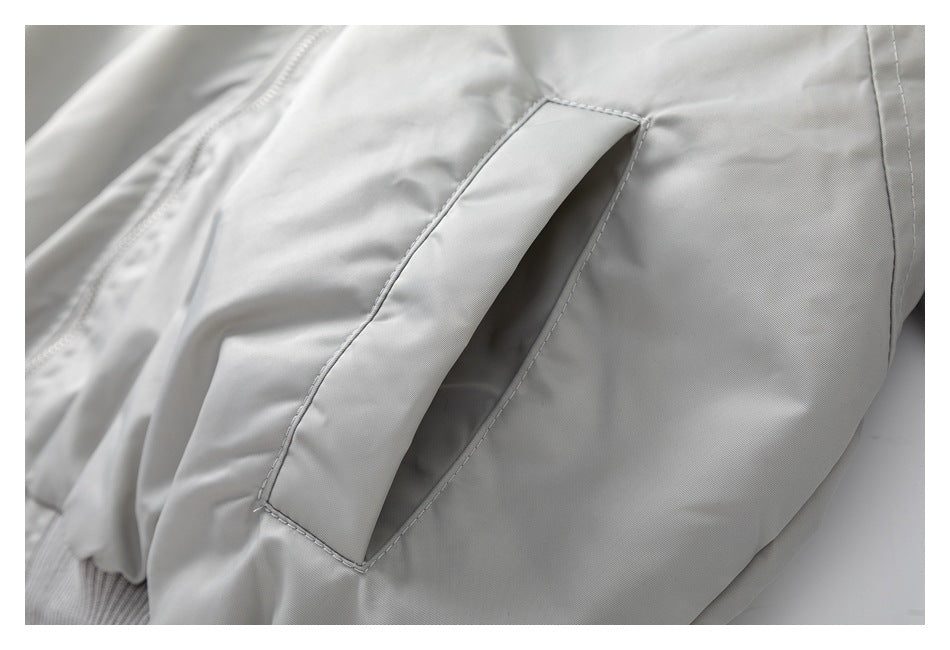 Close-up of a slanted welt pocket on the light gray jacket.