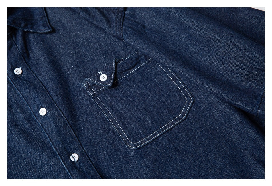 Close-up of a buttoned patch pocket with contrast stitching on a dark indigo shirt.