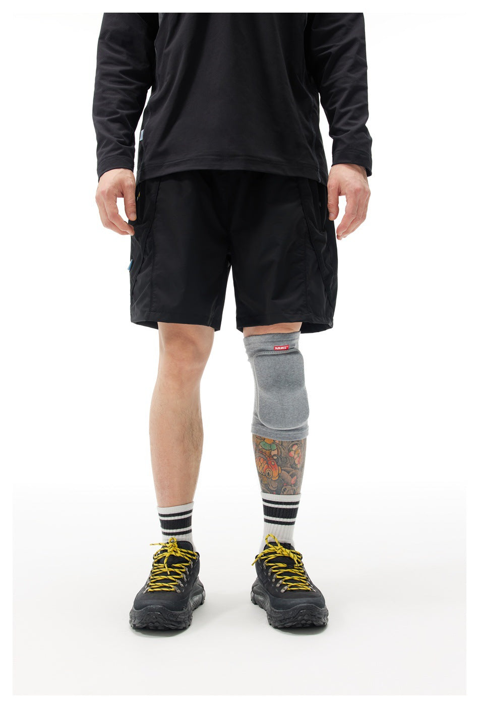 Front view of a model wearing black athletic shorts with side pockets and a black long-sleeve top.