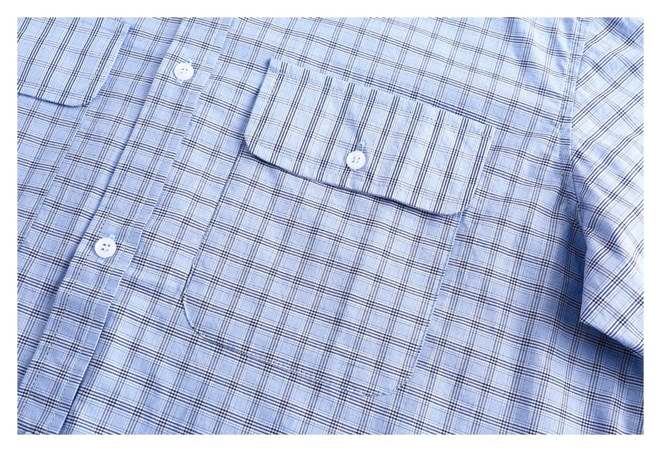 Close-up of a light blue plaid shirt front with a buttoned chest pocket and white buttons.