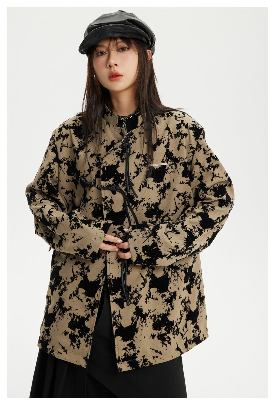 Model wearing a tan jacket with an irregular black pattern, toggle closures and wide sleeves.
