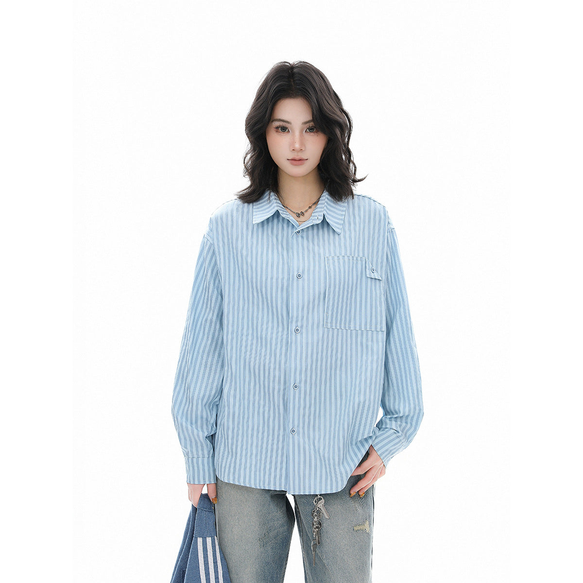 Model wearing an oversized light blue and white vertically striped button-up shirt with a chest pocket.