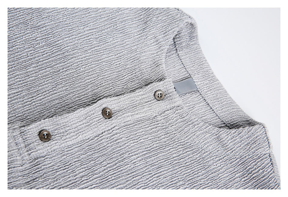 Close-up of the light gray top's textured fabric, brown buttons, and plain neck label.
