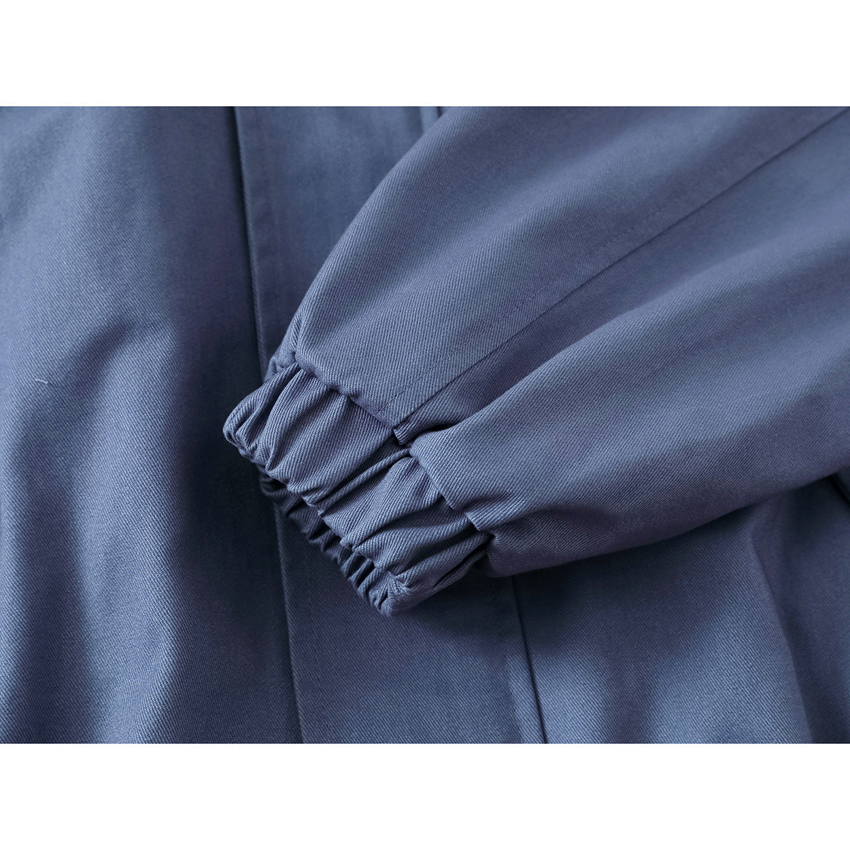Close-up of a blue jacket sleeve with a gathered elastic cuff and visible stitching.
