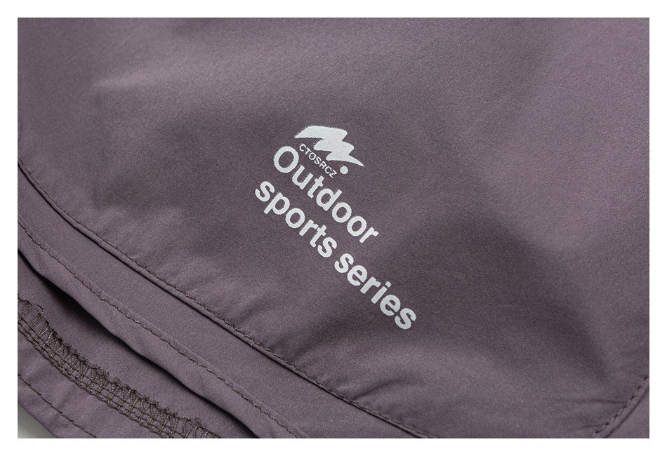 Close-up of mauve-gray shorts with a curved stitched hem and white “Outdoor sports series” print.