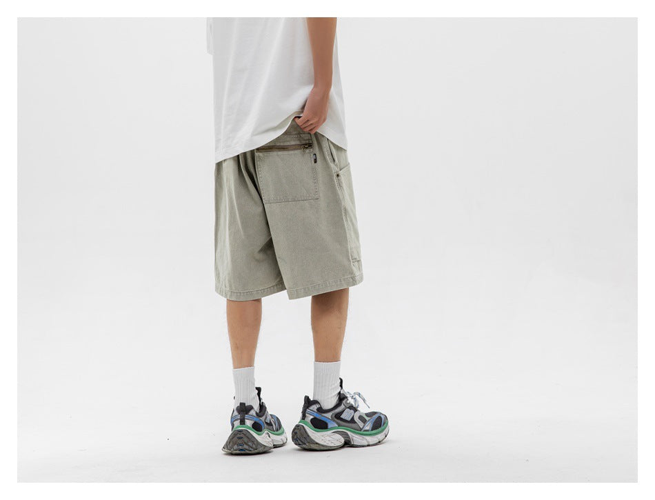 Rear view of a model wearing loose light gray-green shorts with a zippered back pocket.