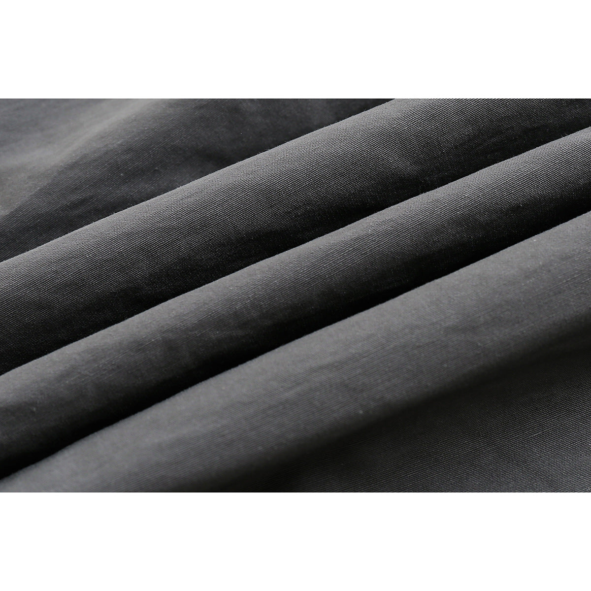 Extreme close-up of dark gray fabric arranged in folds, showing its surface texture.
