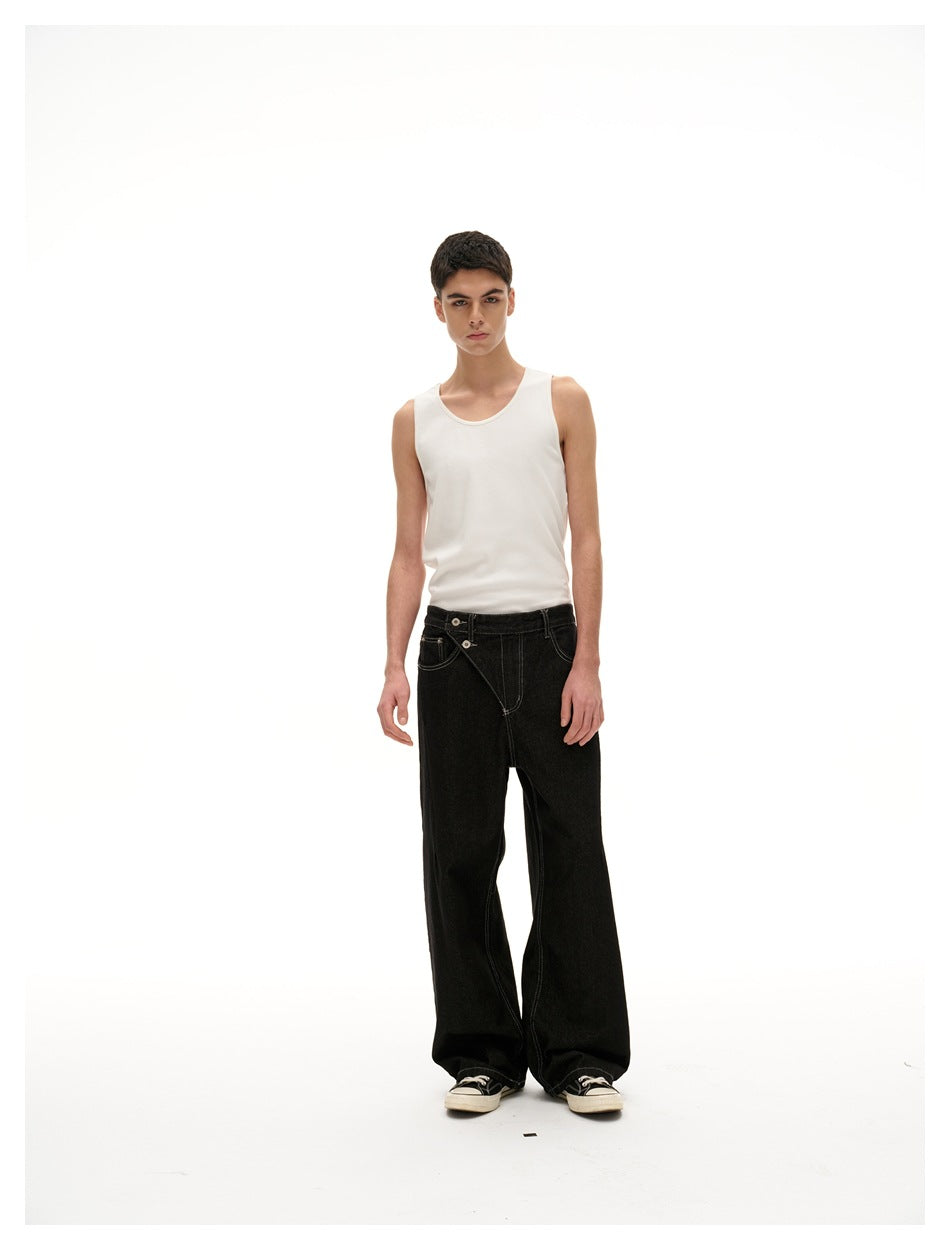 Model in a white tank top and black wide-leg jeans with diagonal button front and sneakers, standing facing forward