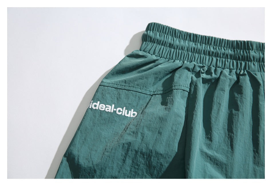 Close-up of the elastic waistband and white ideal-club logo on teal shorts.