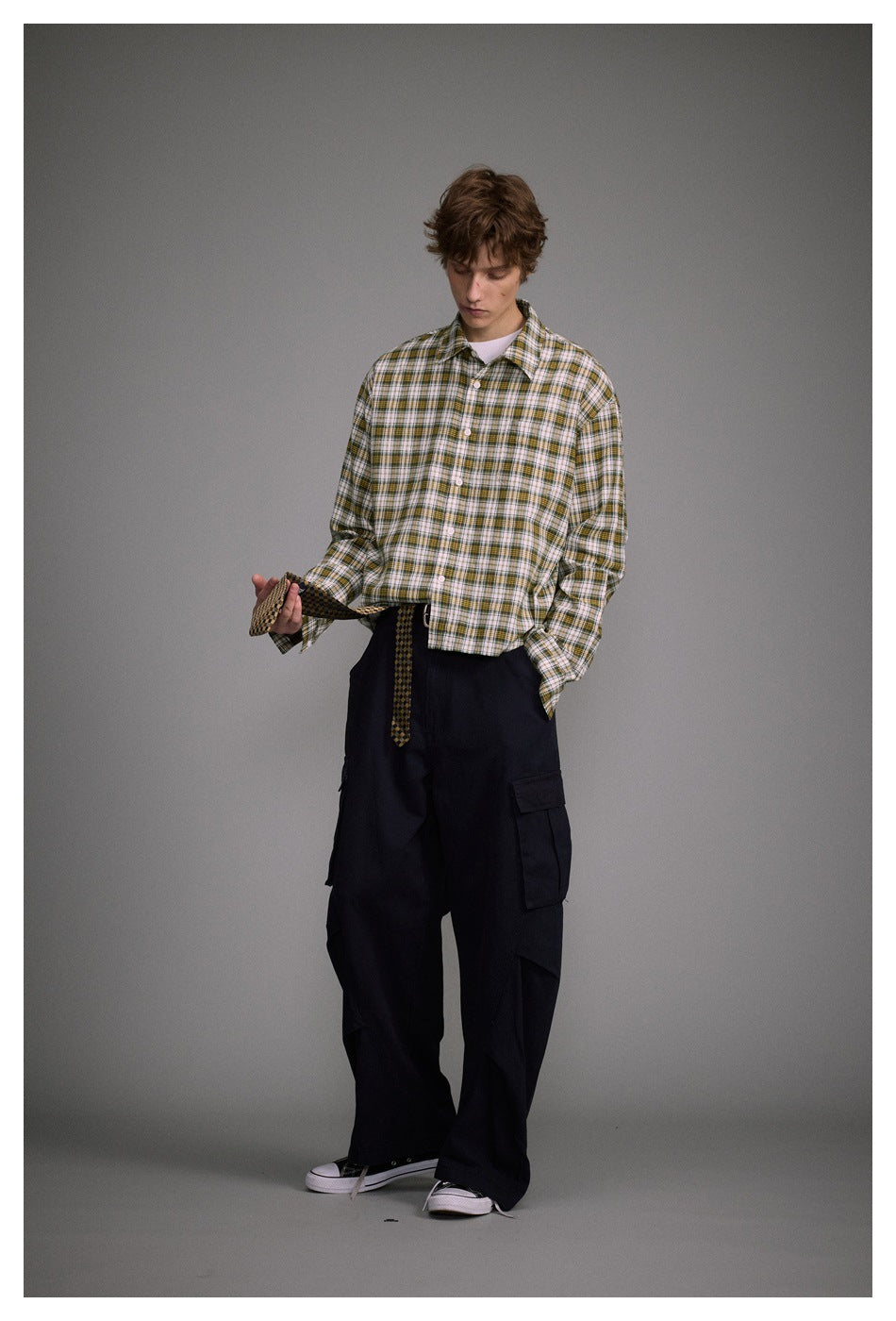 Model wearing a yellow-green plaid cropped shirt over a white tee with black cargo pants and sneakers