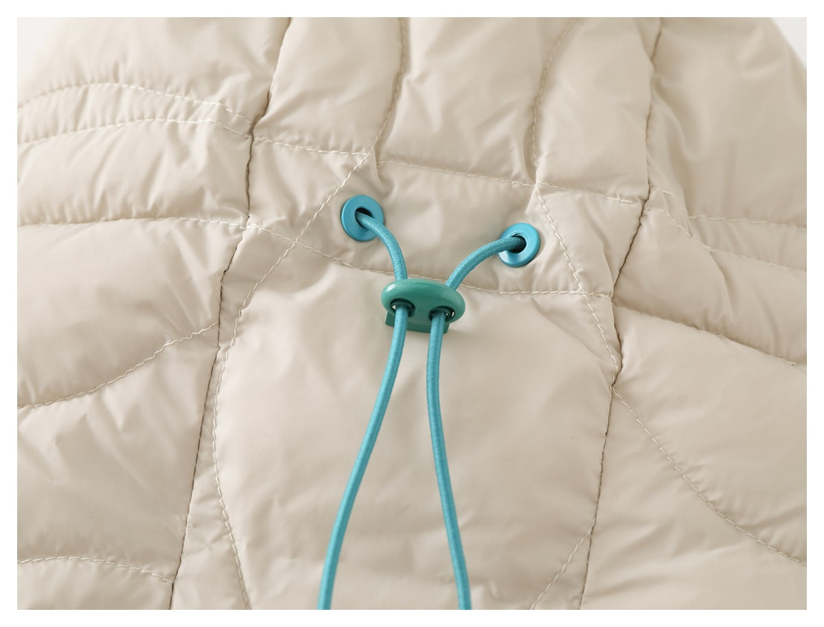 Close-up of a teal adjustable drawcord and toggle on the cream quilted jacket.
