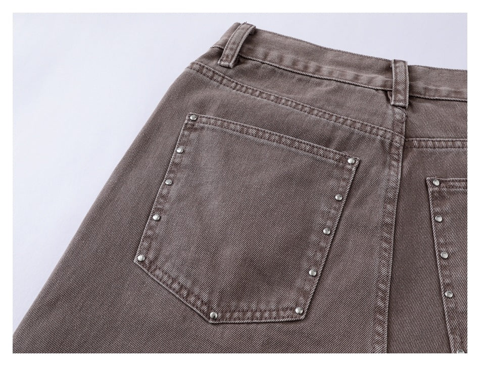 Close-up of a taupe jeans back pocket with metal studs along its edges and waistband belt loops.