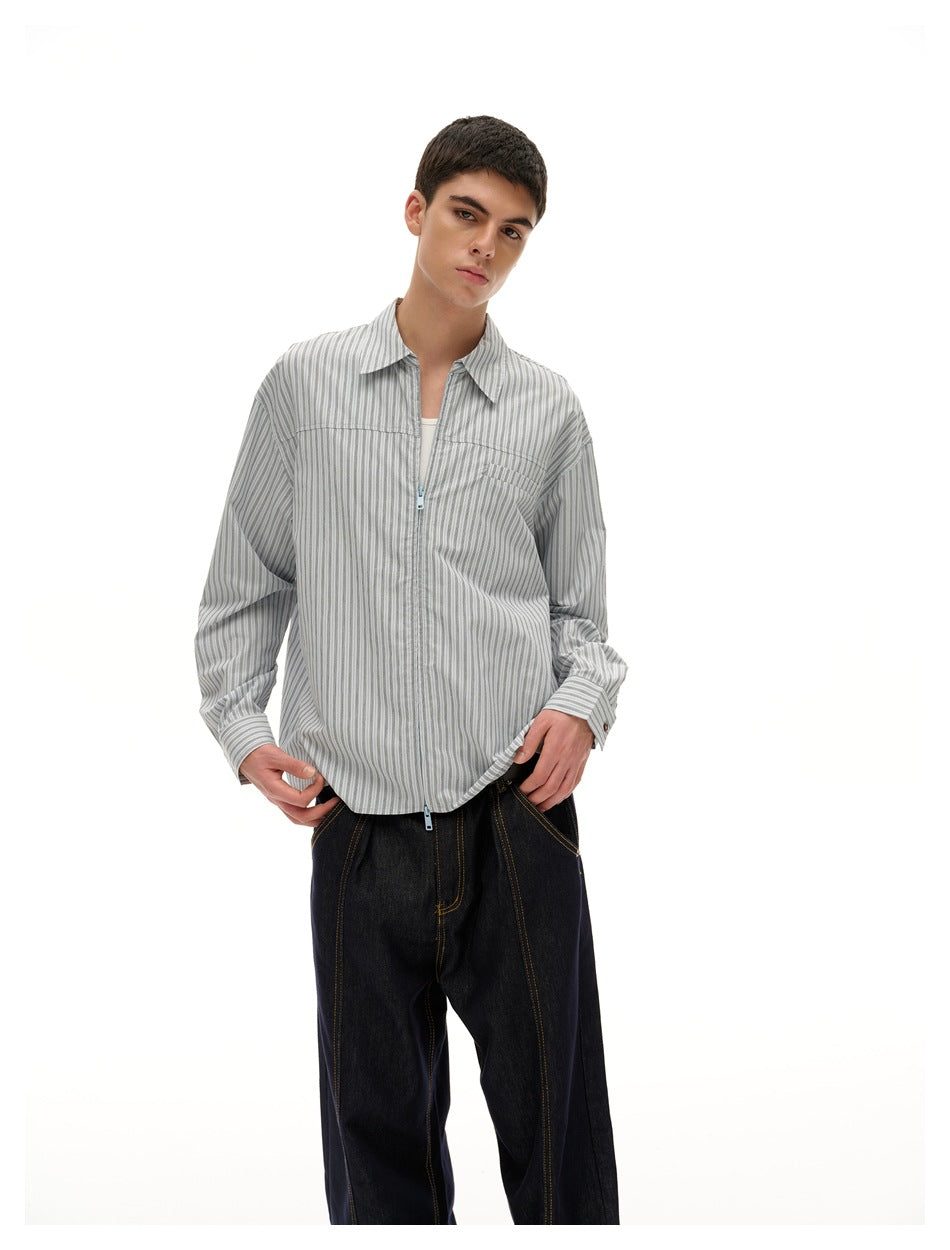 Front view of a model wearing a gray vertical-striped collared shirt with a chest pocket and pale blue zipper.