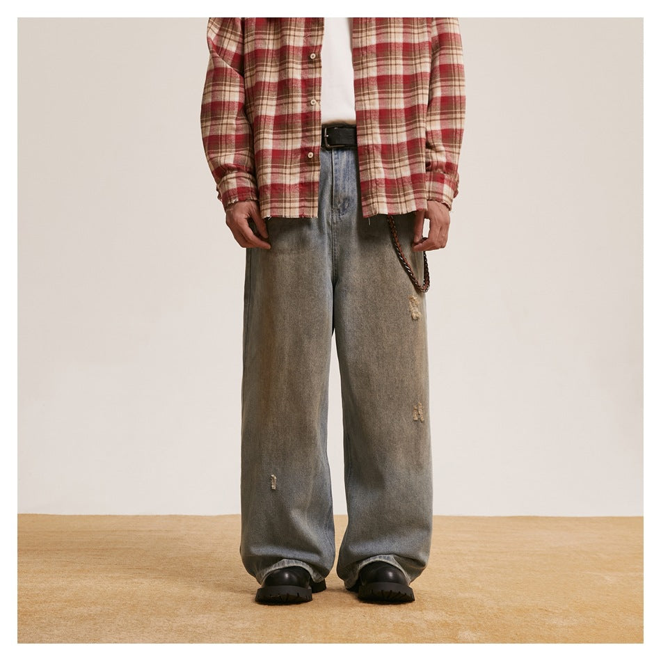 Model wearing faded blue wide-leg jeans with a red plaid shirt, belt, wallet chain and black boots, front view