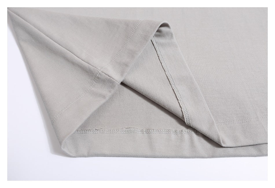 Close-up of the light gray shirt's turned-up hem and overlock stitching.