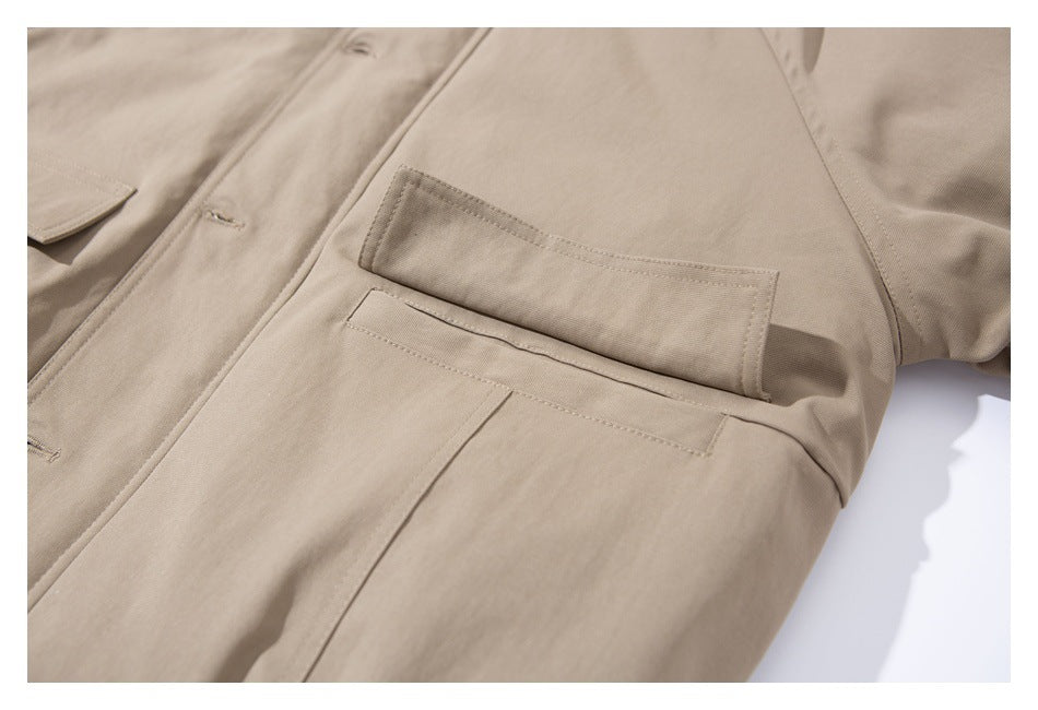 Close-up of a beige jacket showing a flap pocket above a narrow welt pocket with visible stitching.