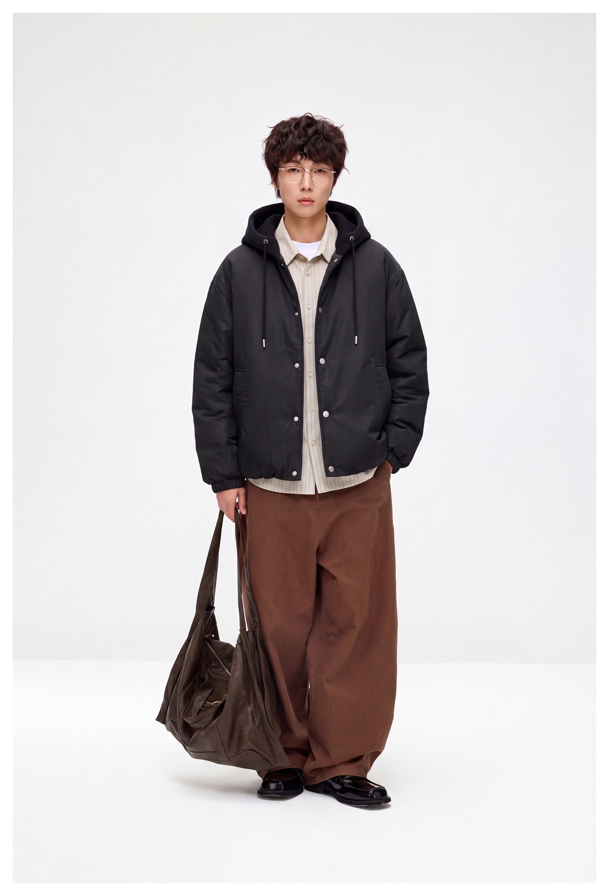 Full-length model wearing a black hooded jacket with snap-front closure and side pockets.