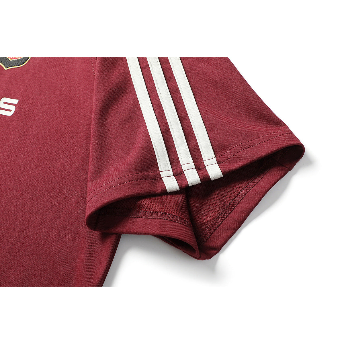 Close-up of a burgundy shirt sleeve with three white stripes and a stitched hem; partial shirt graphics appear at the edge.