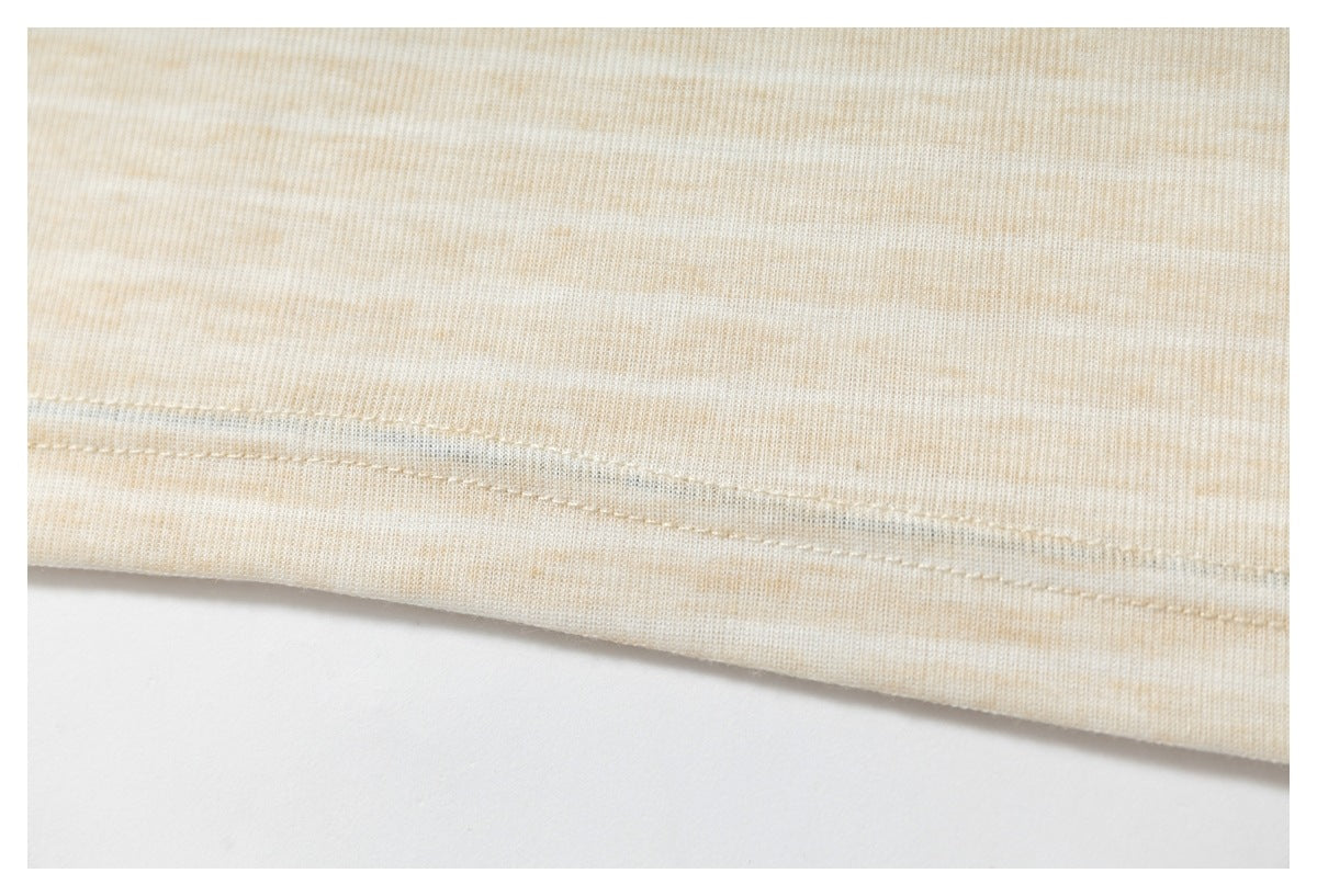Close-up of a stitched hem on cream and beige subtly striped knit fabric.