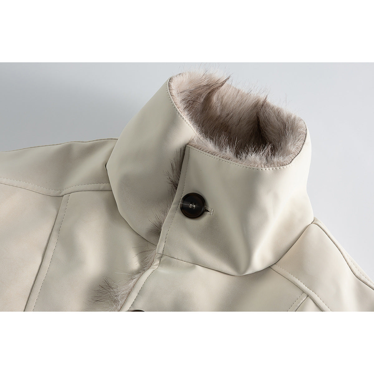Close-up of an ivory jacket’s tall collar, soft taupe lining, dark button, and stitched panels.