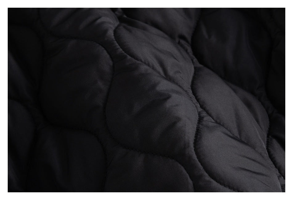 Close-up of black quilted jacket fabric with curved stitched sections.