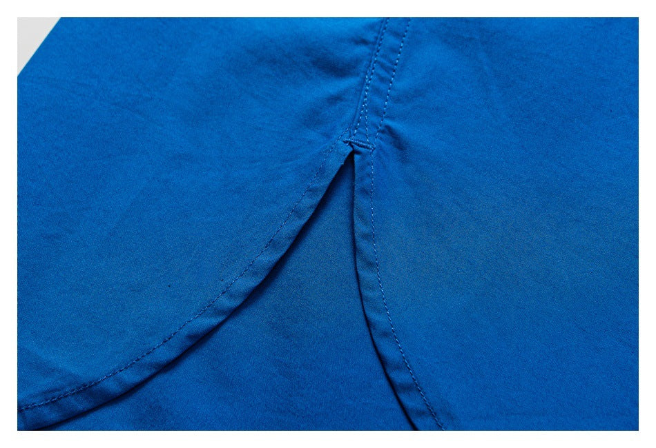 Close-up of bright blue garment fabric with a curved stitched seam and overlapping panel.