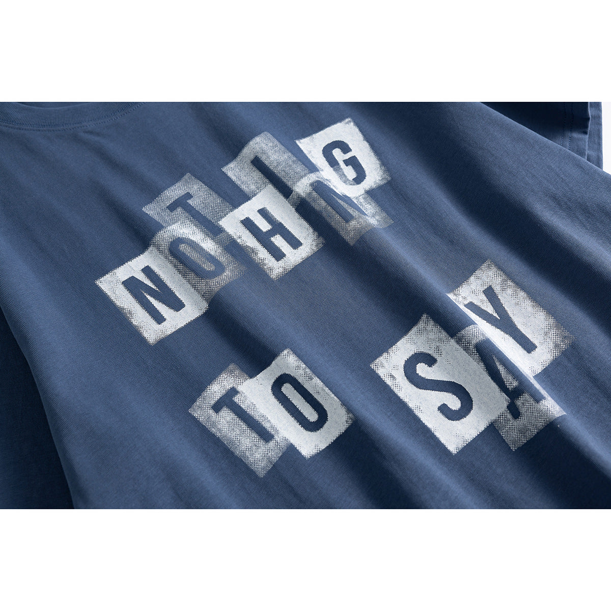 Close-up of a slate-blue T-shirt with distressed white block-letter graphic print.