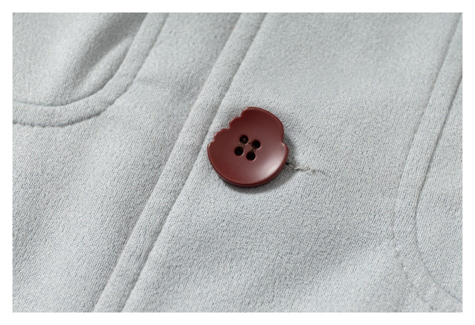 Close-up of a burgundy four-hole button on the light gray coat.