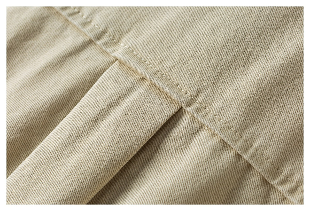 Close-up of beige twill fabric with a diagonal stitched seam and folded edge.