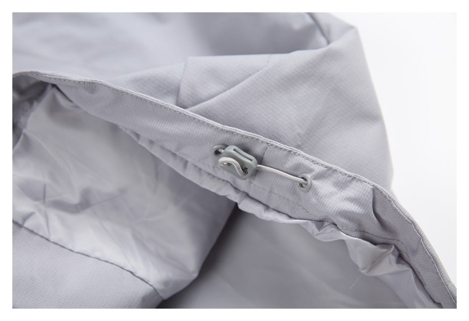 Close-up of a light gray jacket's inner drawcord and plastic toggle.