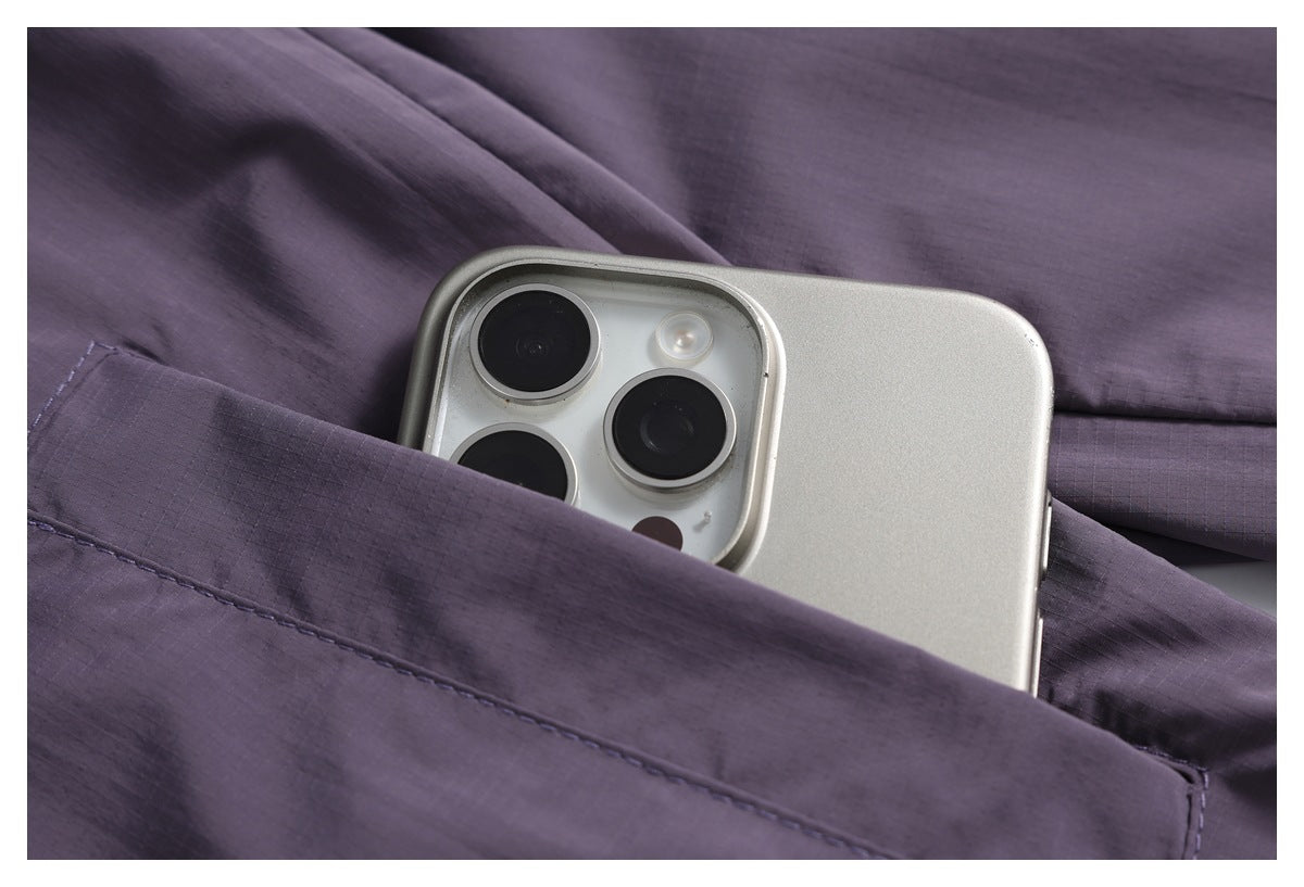 A silver smartphone tucked into a pocket of a dark purple jacket.