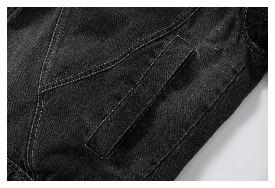 Close-up of a black denim jacket's side seam and narrow rectangular fabric tab.