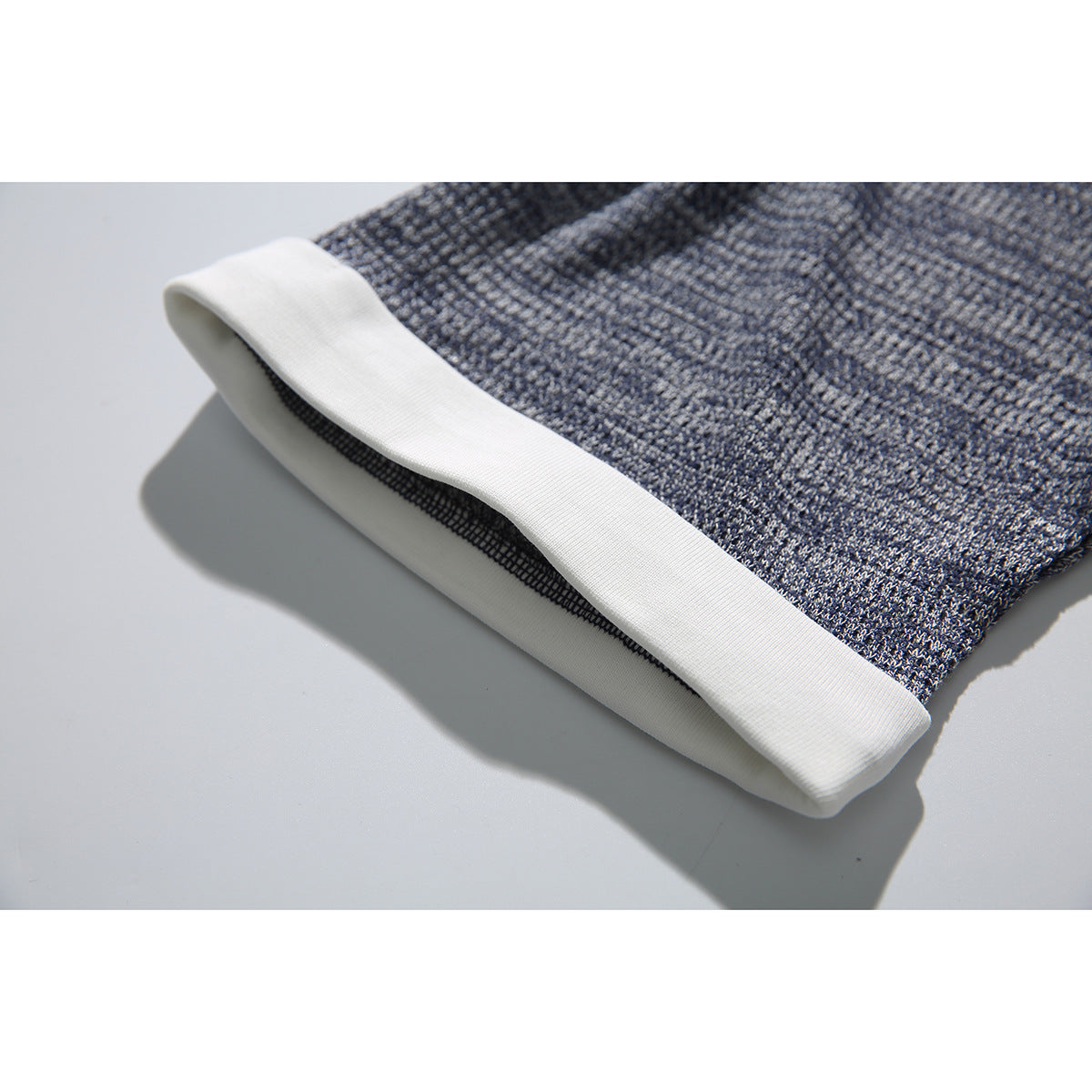 Close-up of a blue-gray textured shirt sleeve finished with a wide white cuff.