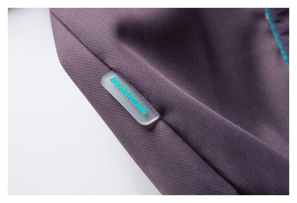 Close-up of purple fabric with a small turquoise branded tab attached at the seam.