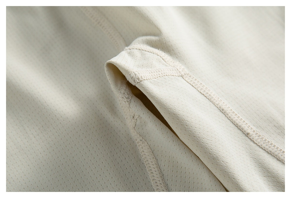 Close-up of a stitched opening and seam on the cream garment's textured fabric.