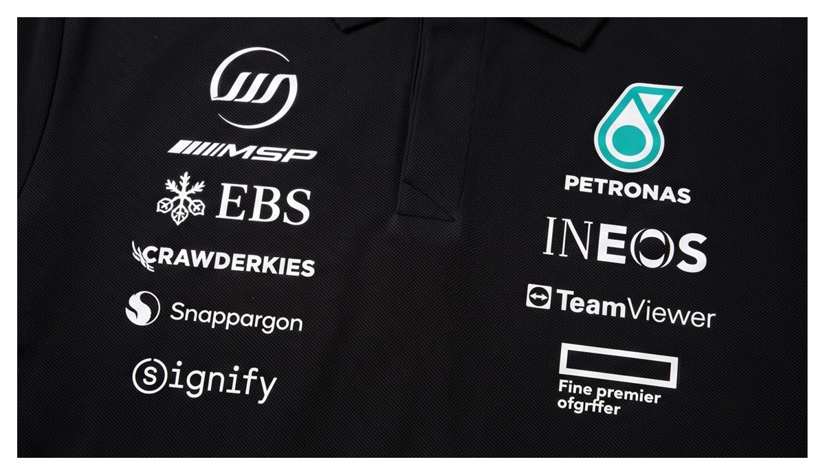 Close-up of a black collared shirt front with white and teal sponsor-style logos printed on the chest.