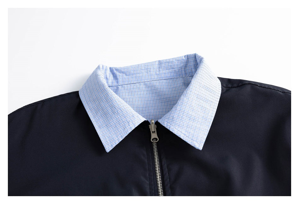 Close-up of a light blue checked collar and metal zipper on a navy jacket.