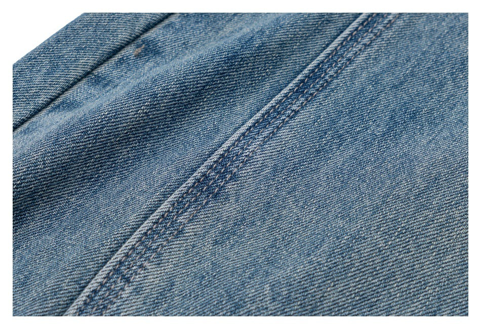 Close-up of faded blue denim fabric with a diagonal double-stitched seam.