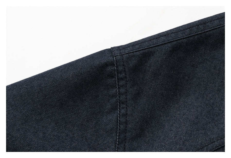 Close-up of dark indigo jacket fabric showing a stitched seam and panel construction.