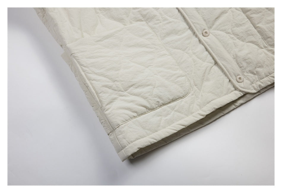 Close-up of the ivory jacket's patch pocket, quilted fabric, and folded hem.