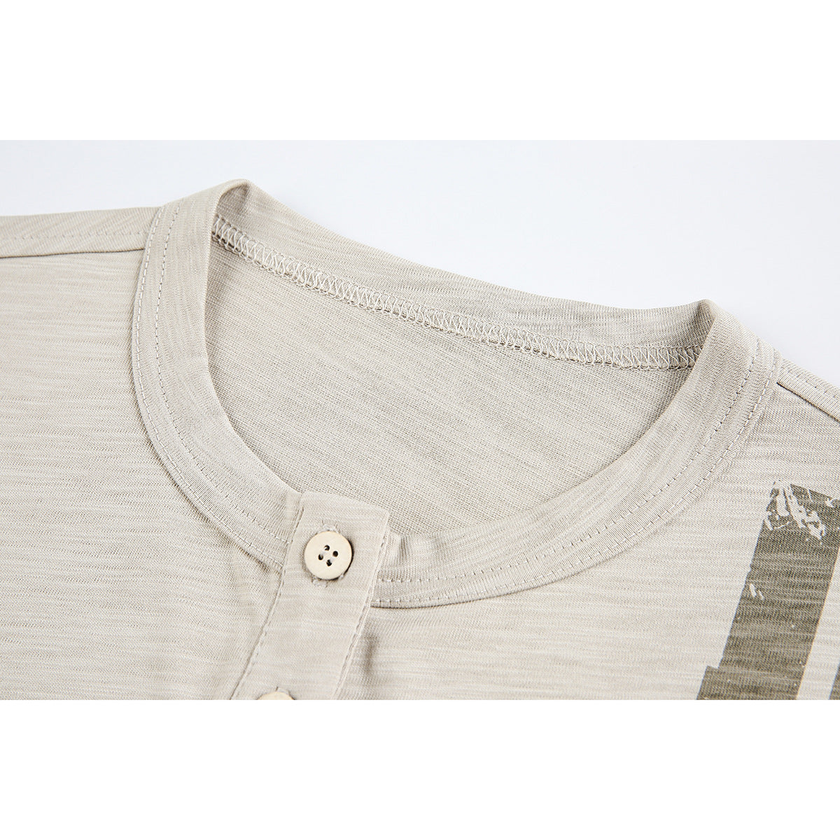 Close-up of a beige T-shirt’s crew neckline, button placket, stitching, and partial distressed print.