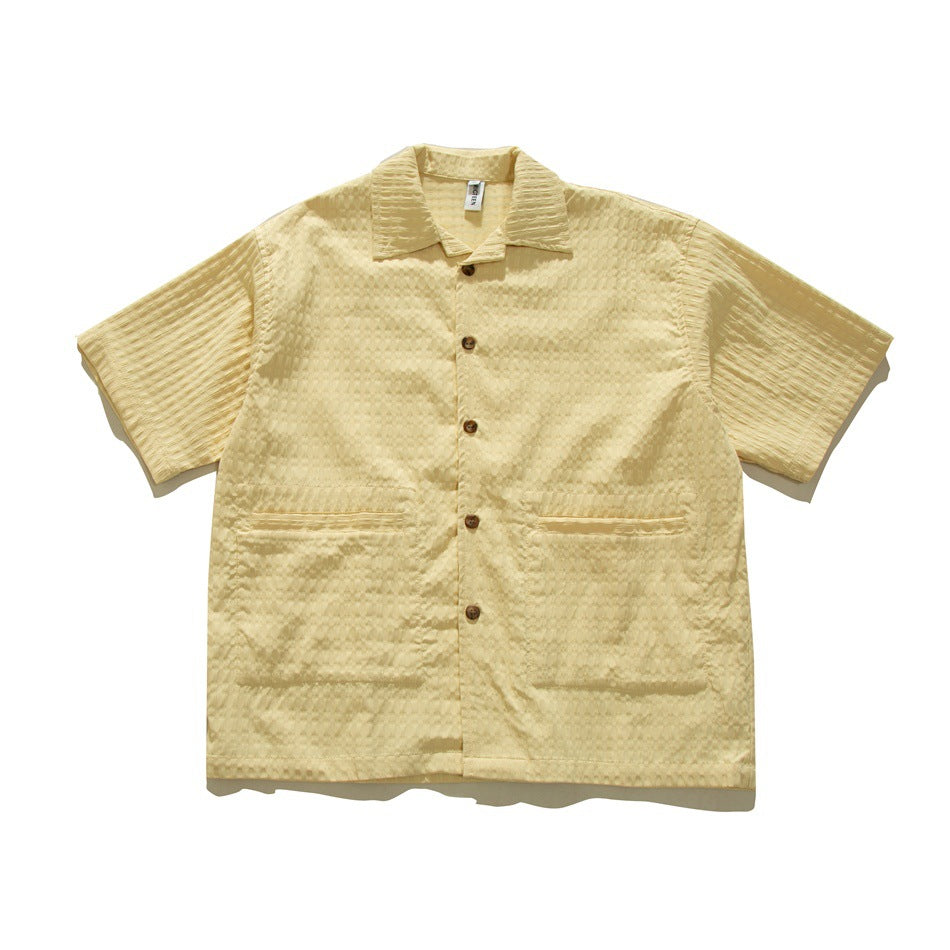 Light yellow short-sleeve textured button-up shirt with collar and two large front patch pockets, flat lay