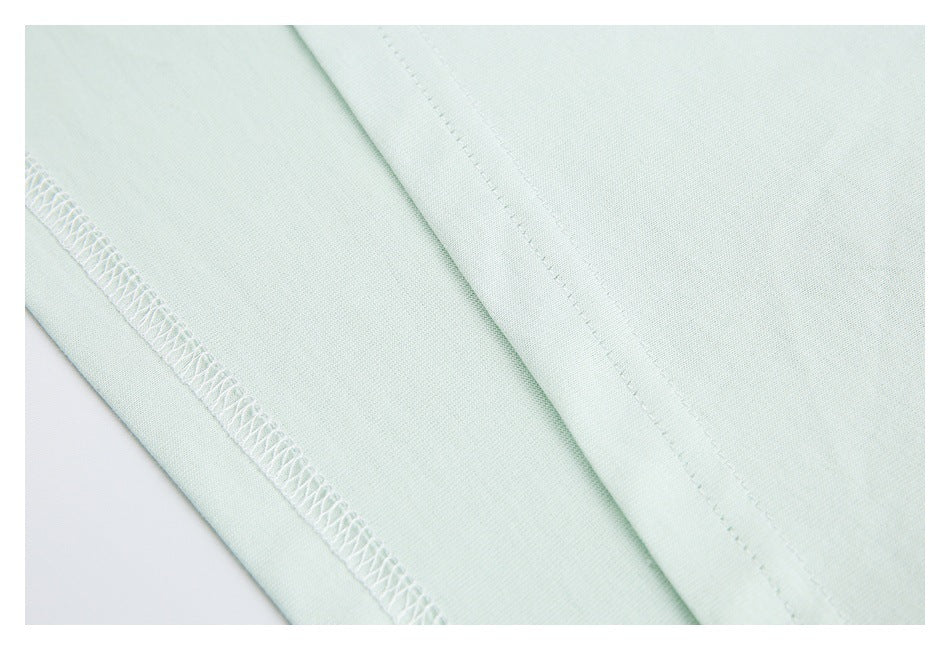 Close-up of pale mint fabric showing a folded edge and overlock stitching.