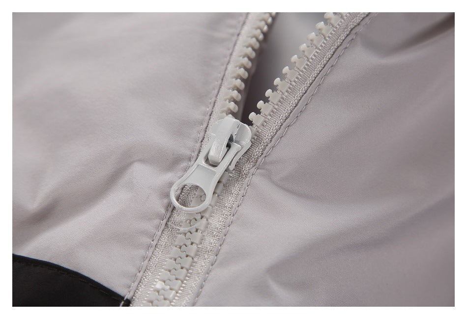 Close-up of a light gray jacket's chunky plastic zipper and pull.