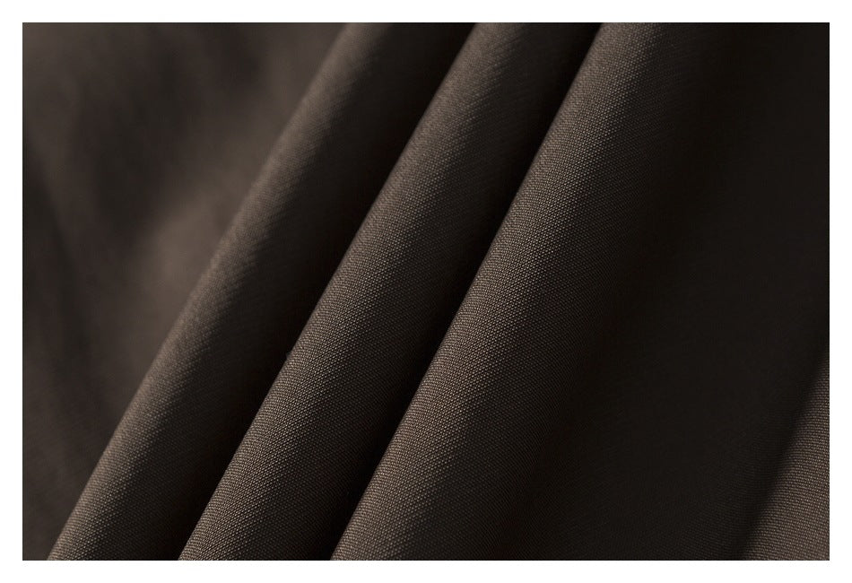 Close-up of dark brown fabric arranged in soft folds, showing its fine woven texture.
