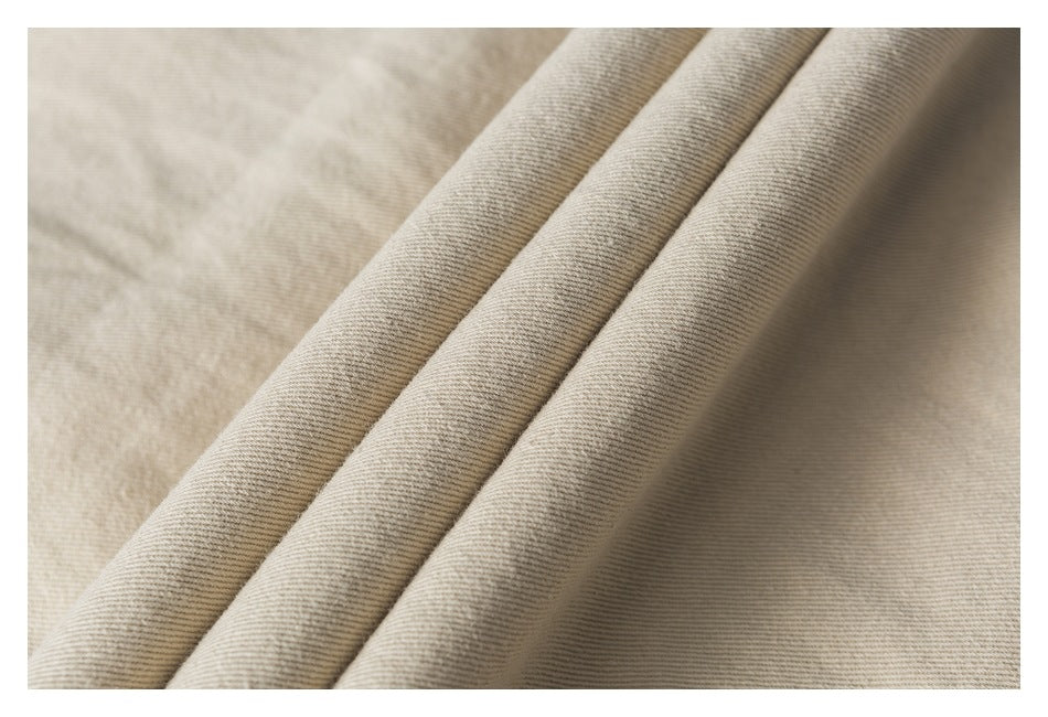 Macro view of beige trouser fabric folded into parallel ridges.